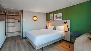 a bedroom with a white bed and a green wall at Campanile NATURE - Poitiers Sud Aeroport in Poitiers +24 photos