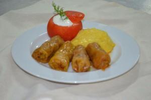 a plate of food with sausage and scrambled eggs and a tomato at Hotel Rodewisch in Rodewisch