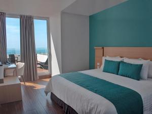 a bedroom with a bed and a desk and a window at Hotel Plaza Sol Veracruz in Veracruz