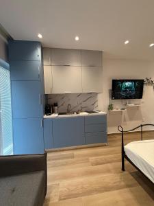 a kitchen with blue cabinets and a flat screen tv at Drymades Studio Apartment in Gjilek