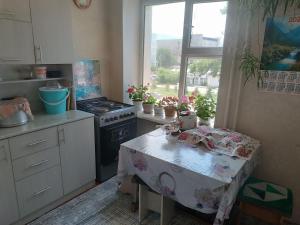 a kitchen with a table and a stove and a window at Beka guest house in Karakol