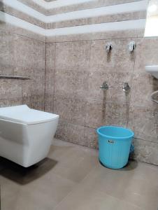 a bathroom with a toilet and a blue bucket at Elegant Inn Hotel in Surat