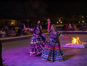 two women are dancing in front of a fire at Best desert camp in jaisalmer The Velvet Dunes in Sām