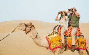 two people riding on a camel in the desert at Best desert camp in jaisalmer The Velvet Dunes in Sām