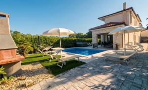 a pool with chairs and umbrellas next to a house at Luxury Villa Aramis with jacuzzi in Malinska in Sveti Ivan