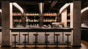Eine Bar mit Hockern in einem Raum mit Alkohol in der Unterkunft Ruby Leni Hotel Dusseldorf by IHG in Düsseldorf