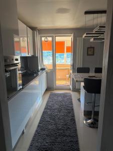 a kitchen with a large window and a kitchen with a rug at Cu Tâmpa la fereastră - Spacious Apartment with Mountain View & 2 Free Parking Spaces in Braşov