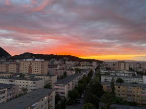 a city skyline with a sunset in the background at Cu Tâmpa la fereastră - Spacious Apartment with Mountain View & 2 Free Parking Spaces in Braşov +3 photos
