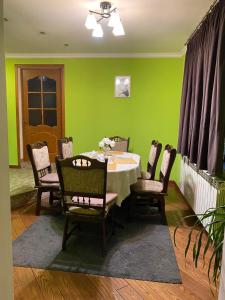 a dining room with a table with chairs and green walls at Літо in Bushtyno +5 photos