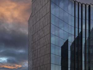 a tall glass building against a cloudy sky at Pullman Auckland Airport in Auckland