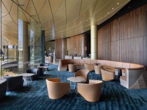 a lobby of a hotel with tables and chairs at Pullman Auckland Airport in Auckland