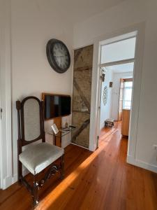 a living room with a clock on the wall and a chair at Otília Apartamentos in Lisbon