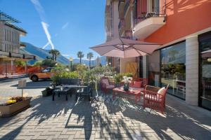 a patio with tables and chairs and an umbrella at Foresteria BB Sul Lago in Porlezza