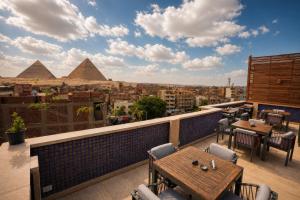 a balcony with tables and chairs and the pyramids at Pyramids Hostel in Cairo