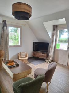 a living room with a tv and a table at Le Village du Moulin in Sizun