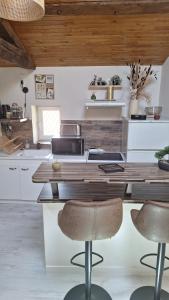 a kitchen with a wooden counter with two bar stools at La tête dans les étoiles - Appartement climatisé - 2 Chambres in Ruffec +14 photos