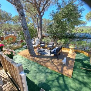 a backyard with a wooden deck with chairs and a tree at Camping les cigales 5 étoiles in Le Muy