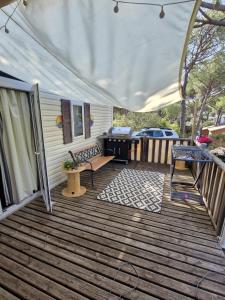 a covered deck with a grill and a bench at Camping les cigales 5 étoiles in Le Muy