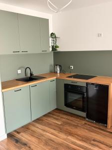 a kitchen with white cabinets and a black dishwasher at Apartament Lniany in Leszno +24 photos