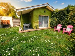a green house with two pink chairs in the yard at Gîte 2 pers avec jardin entre Bordeaux & Lacanau Océan in Brach