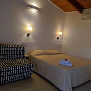 a hotel room with a bed and a chair at Residence Arco delle Rose in Agropoli
