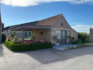 a brick house with a flower garden in front of it at Hoveke Paddebroek in Alveringem