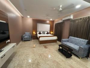 a hotel room with a bed and a couch and a tv at Raj Hussain Land Mark Hotel in Mayiladuthurai +11 photos