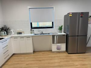 a kitchen with a stainless steel refrigerator and white cabinets at 3BR Haven in Stony Rise in Tugrah