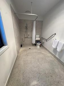 a bathroom with a toilet and a shower with towels at 3BR Haven in Stony Rise in Tugrah