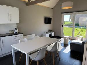 a kitchen and living room with a white table and chairs at Hoveke Paddebroek in Alveringem