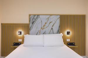 a bedroom with a white bed and gold stripes at Partenope Rooms in Naples