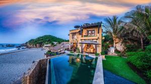 a house with a swimming pool next to the ocean at 1037 - Villa Escondida in Santa Cruz Huatulco