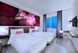 um quarto com uma grande cama branca com flores cor-de-rosa na parede em favehotel Margonda em Depok