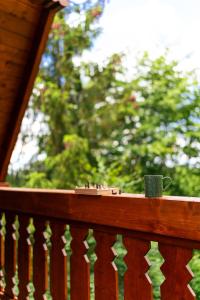 a coffee mug sitting on a wooden railing on a porch at Casa Sunetul Padurii din Belis Apuseni in Călăţele