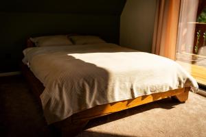 a bed sitting in a bedroom next to a window at Casa Sunetul Padurii din Belis Apuseni in Călăţele