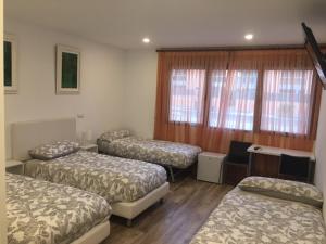 ein Zimmer mit drei Betten, einem Schreibtisch und Fenstern in der Unterkunft Hotel Skyline Boadilla in Alcorcón + 4 Fotos