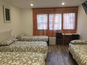 ein Zimmer mit drei Betten und einem Schreibtisch darin in der Unterkunft Hotel Skyline Boadilla in Alcorcón