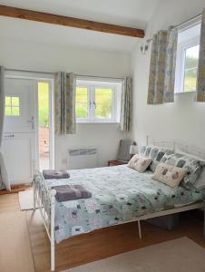 a bedroom with a bed and two windows at Vineyard Barns Gower in Swansea
