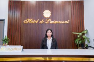 a woman standing behind a table in front of a sign at Laimeront Dalat Hotel & Apartment in Da Lat