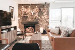 a living room with a couch and a stone fireplace at Modern Mountainside Chalet in Steamboat Springs