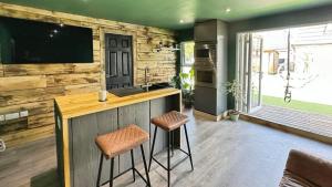 a kitchen with a bar with stools and a tv at Self contained cabin - The VenU in Bristol