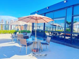a patio with a table and chairs and an umbrella at Move - Tambaú in João Pessoa