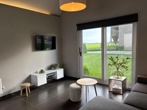 a living room with a couch and a large window at Hoveke Paddebroek in Alveringem
