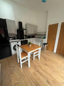 a kitchen with a wooden table with chairs and a stove at Beeston Bungalow in Nottingham