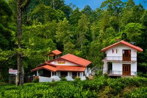 a white house with an orange roof next to a forest at Haputala Blossom guest in Haputale