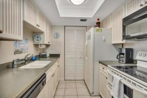 a kitchen with a white refrigerator and a sink at Beach Club 436 in Saint Simons Island