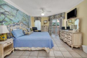 a bedroom with a blue bed and a tv at Beach Club 436 in Saint Simons Island