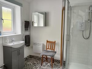 a bathroom with a shower and a sink and a chair at Vineyard Barns Gower in Swansea +43 photos
