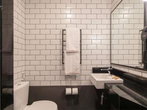 a white bathroom with a toilet and a sink at ibis Tubarão in Tubarão