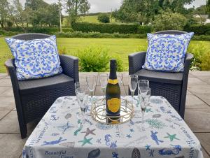 a bottle of wine sitting on a table with glasses at Vineyard Barns Gower in Swansea